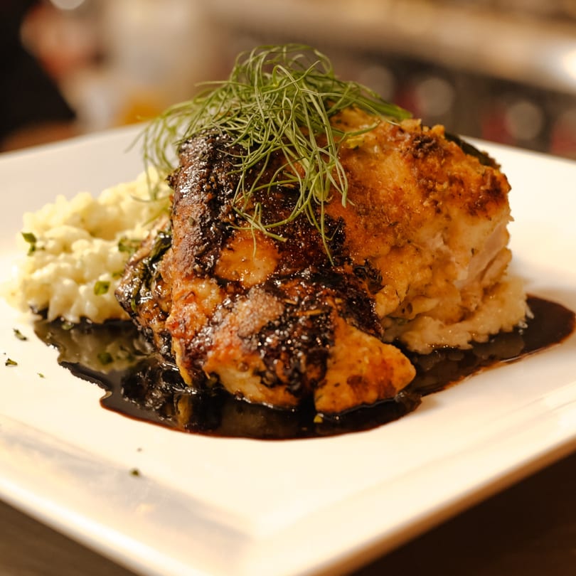 Caffè REL's French dish: a golden-brown chicken breast with dark sauce, mashed potatoes, and dill.